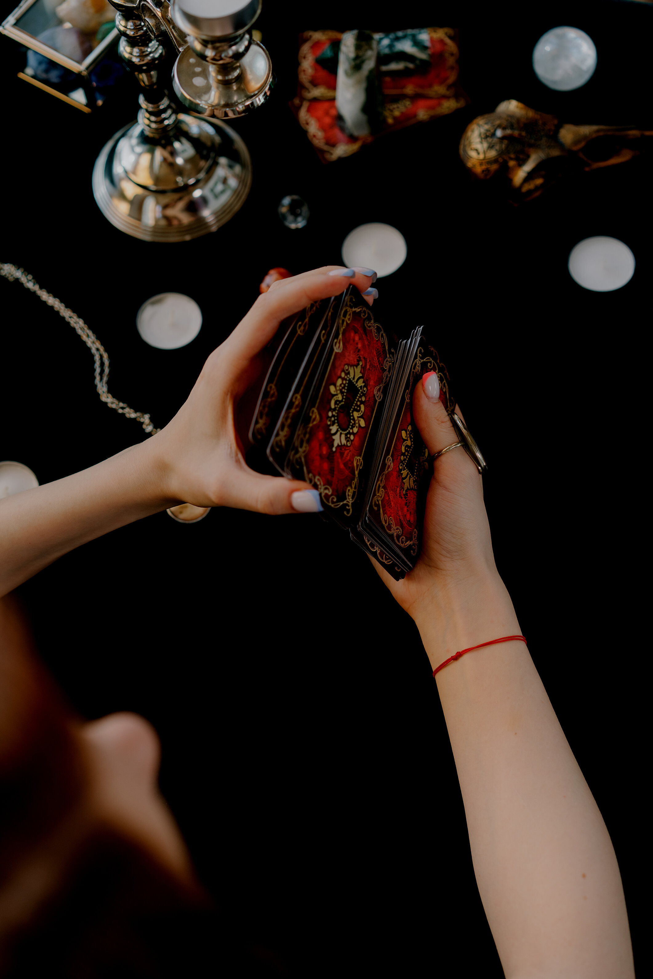 Anonymous female fortune teller shuffling tarot cards at table